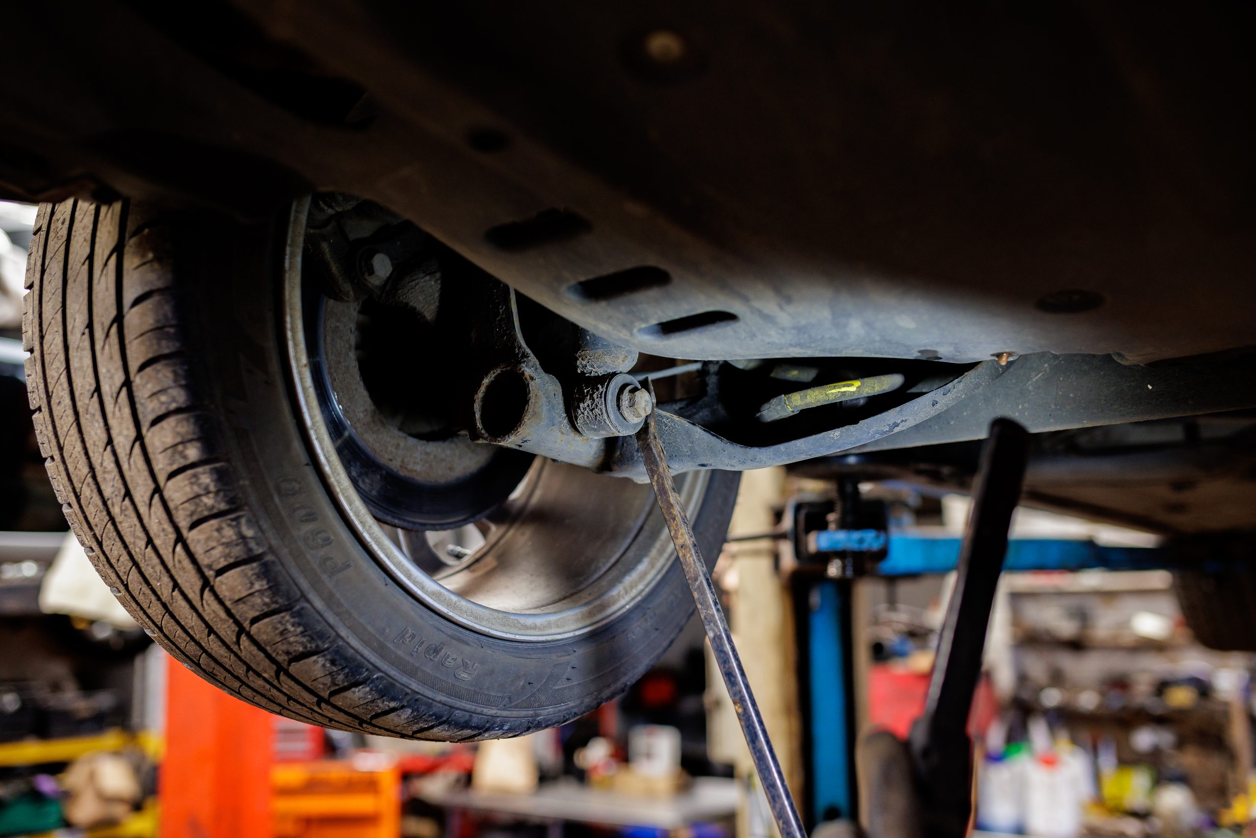 Mechanic working on a suspension component beneath a vehicle